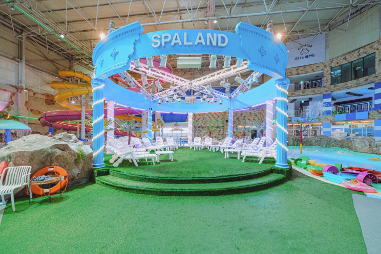 SPALAND 라고 적힌 조형물 아래 인조 잔디를 깔고 흰 선베드를 늘어놓은 휴식 공간